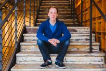 Man in blue shirt sitting on steps and looking at camera