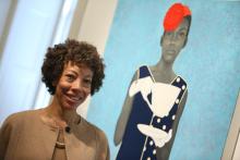 Artist Amy Sherald standing in front of her painting. 