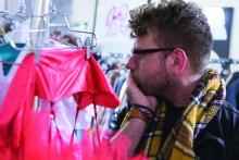 Man in scarf looking at clothes on hangers