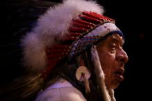 Native man wearing a white headdress in profile