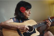 Rosie Flores seated at home playing guitar