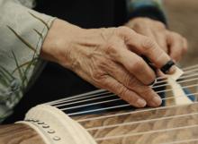 Close up of hand plucking koto strings