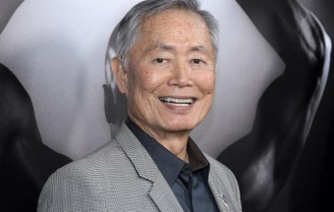 Portrait of Japanese American man wearing gray suit jacket over black shirt. 