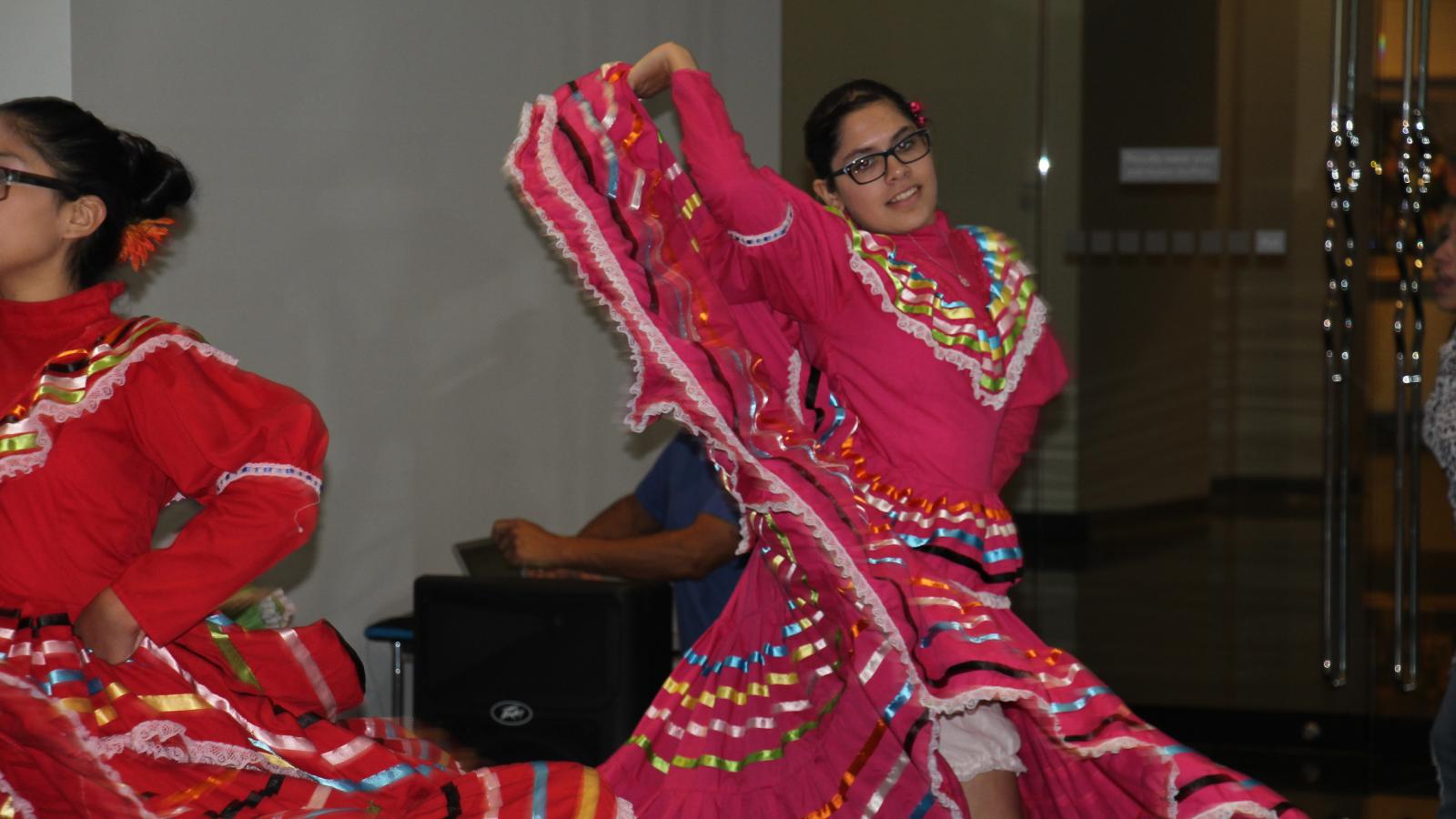 Young Hispanic girl dancing in traditional attire.