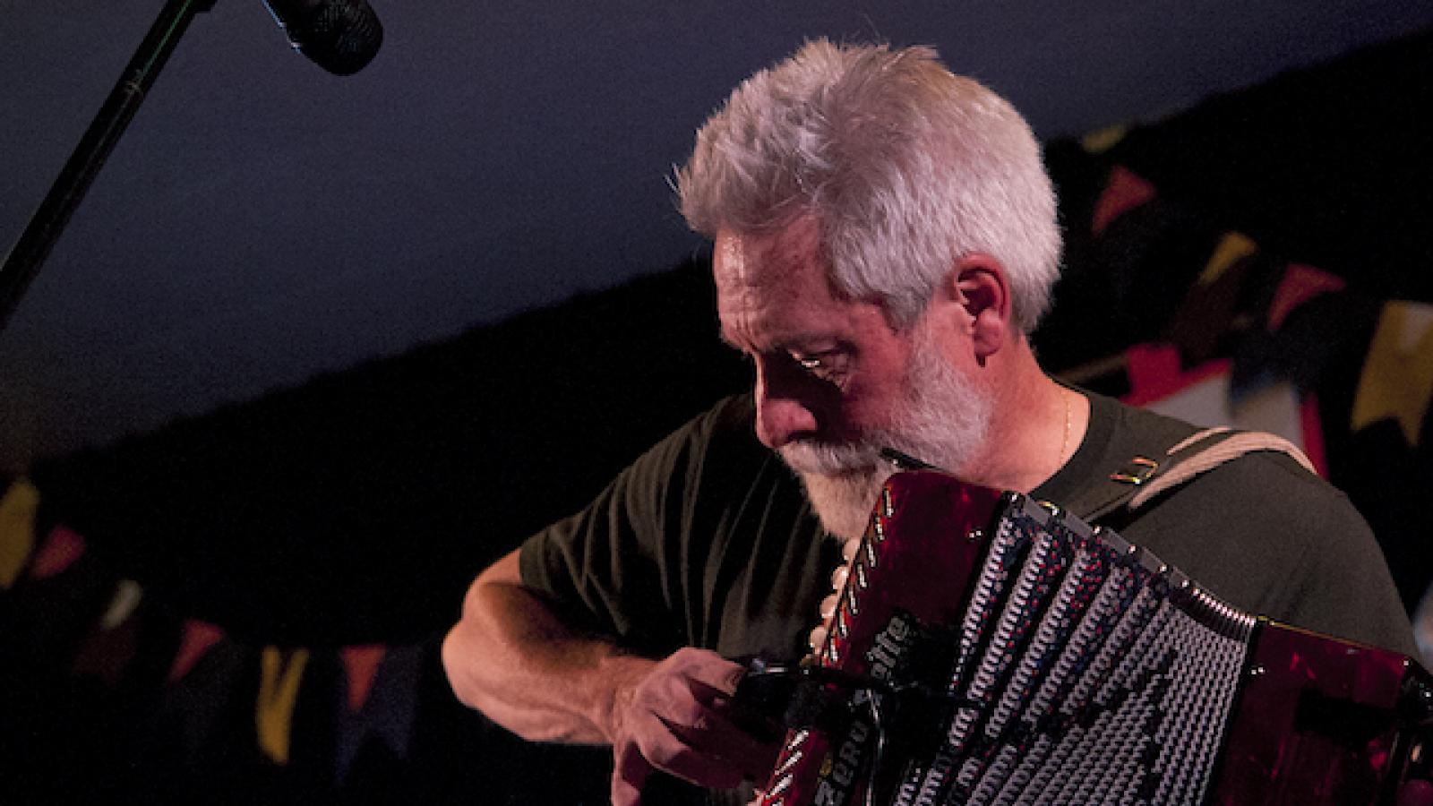 a man with gray hair playing an accordion