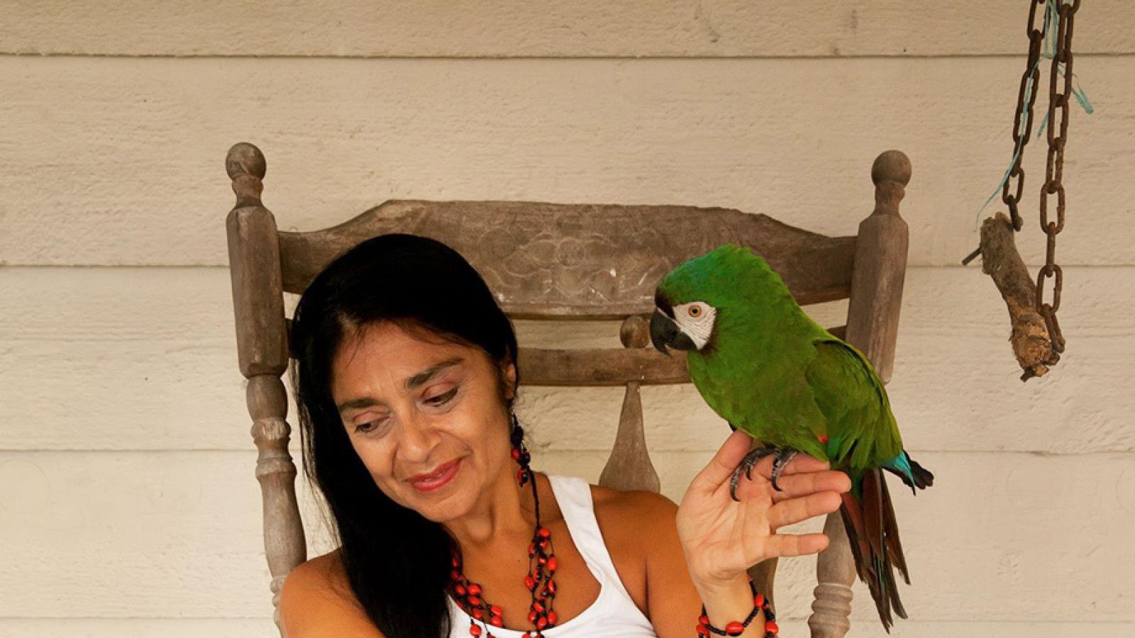 Woman sitting on a bench with parrot on her hand