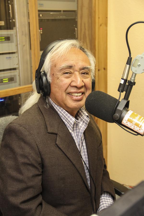 Man with headphones on in front of a radio mic.