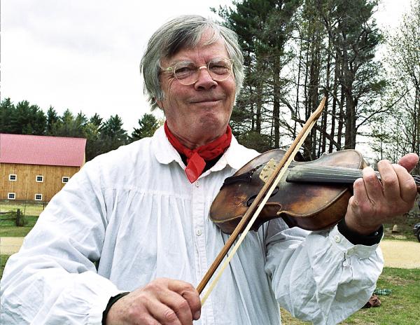 Man playing a fiddle outdoors. 