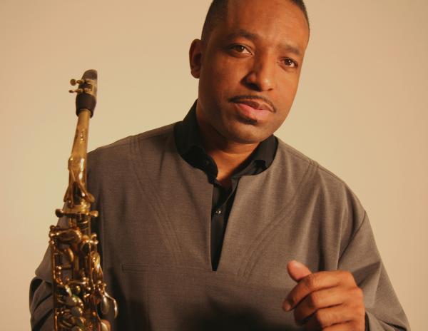 Black man holding a saxophone in his right hand. 