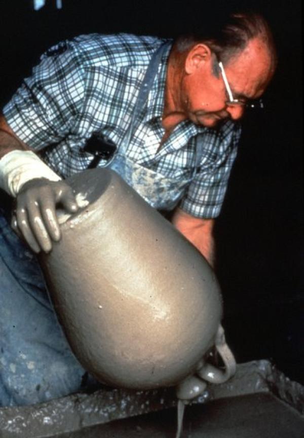 A man holding a cly pot.