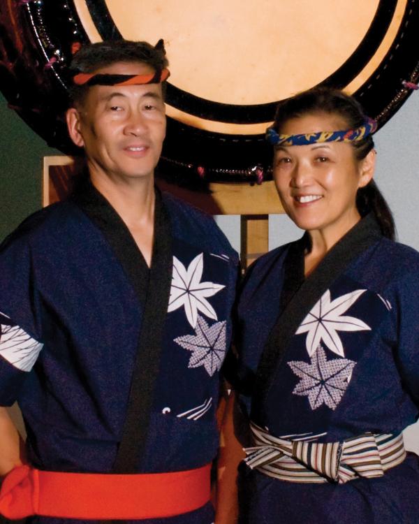 Asian man and woman standing in front of large drum. 